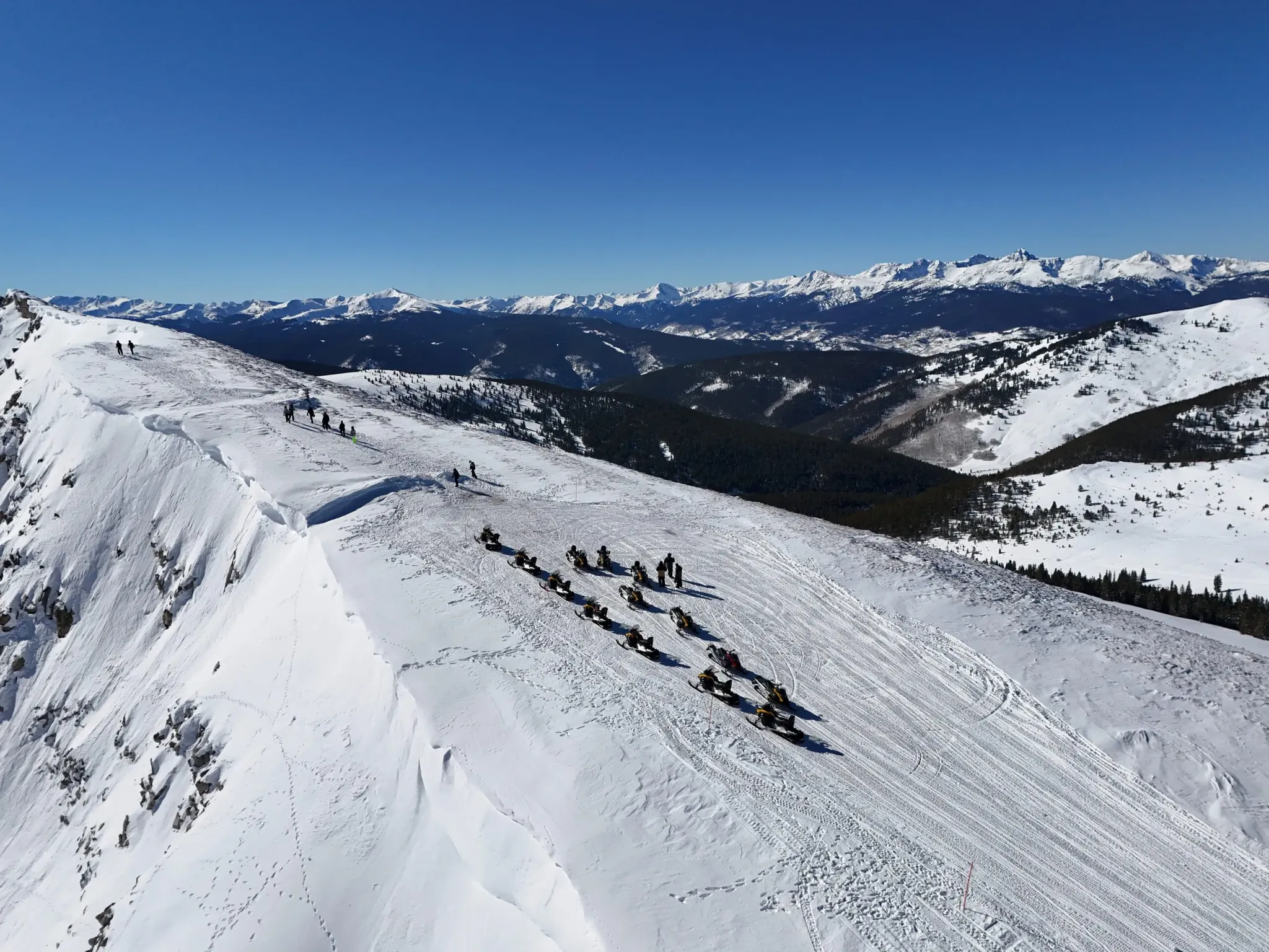 Snowmobile riders on a guided tour near Vail, Colorado with Rocky Mountain views.