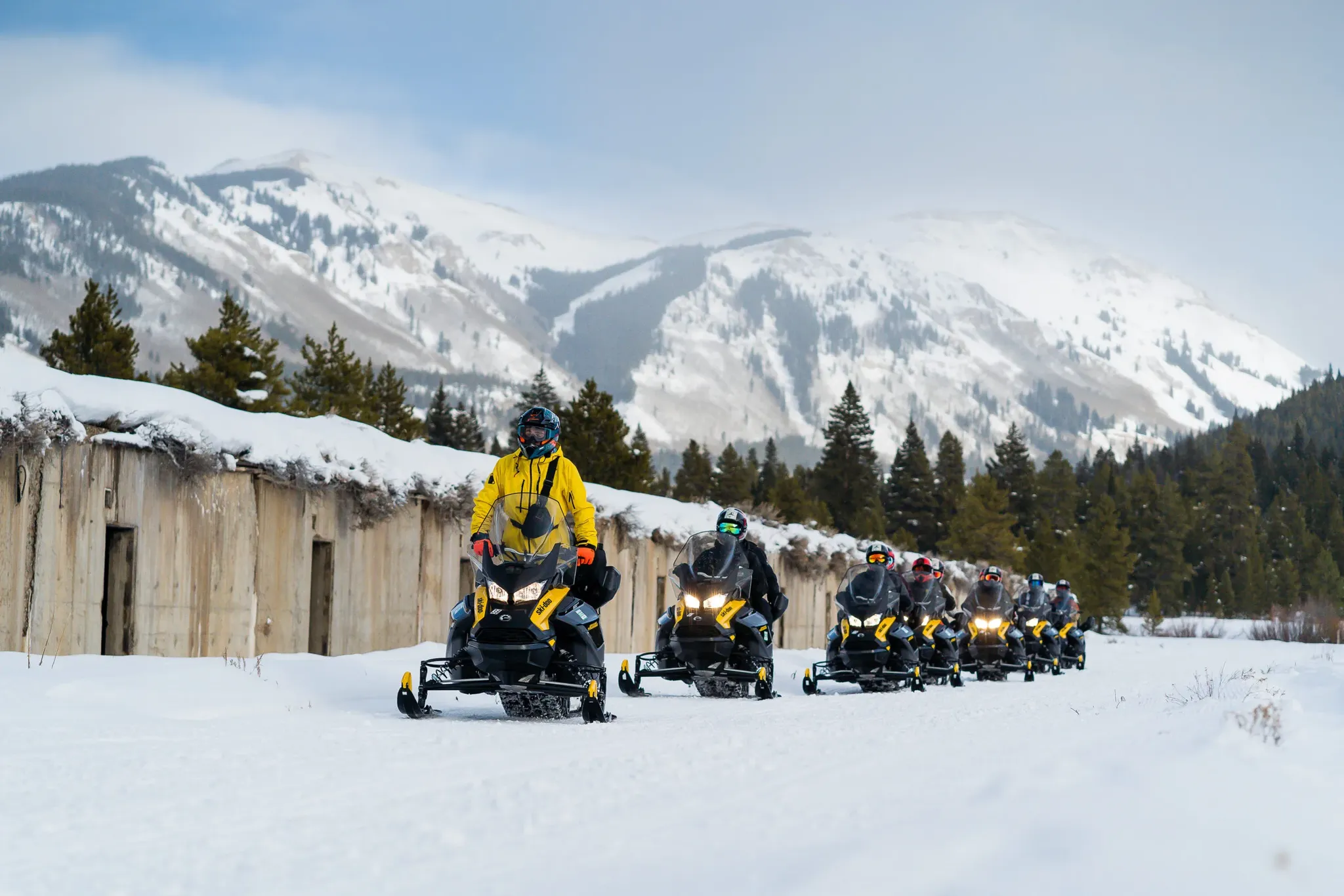 Riders on guided snowmobile tour near Vail Colorado with alpine peaks in background